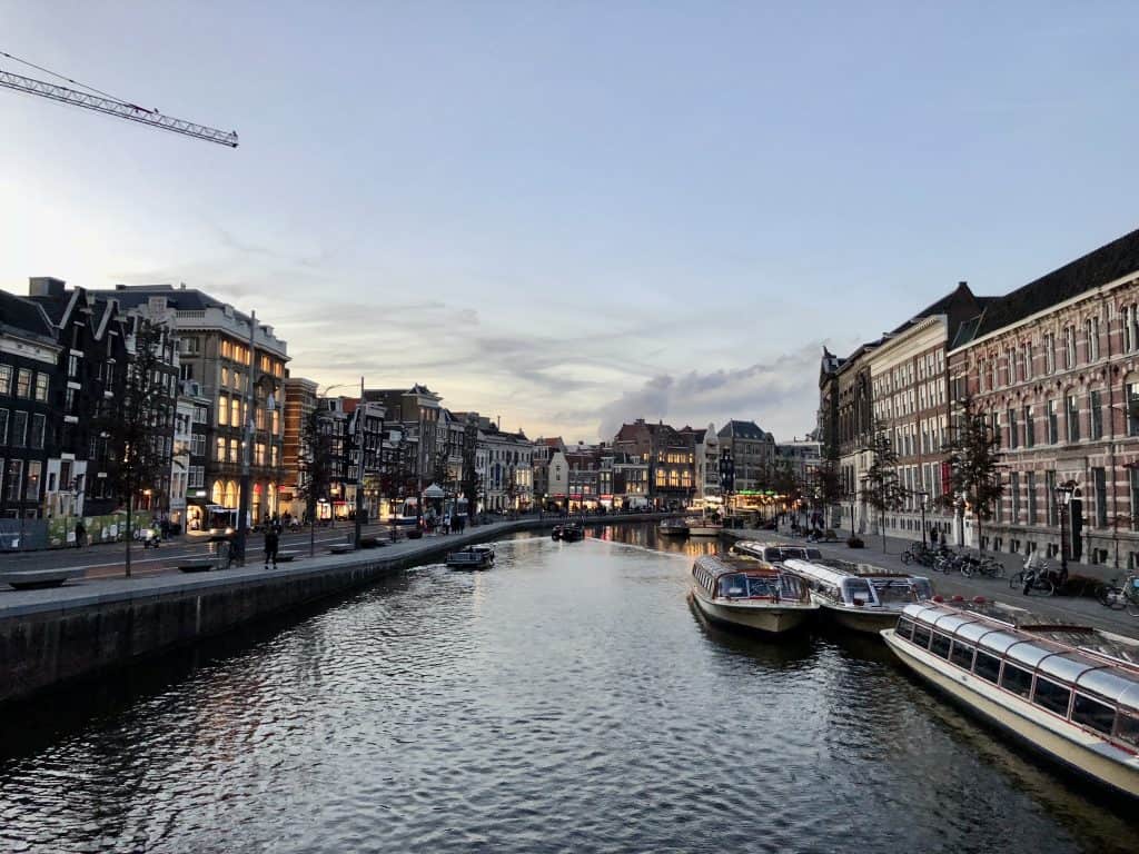Evening view of Amsterdam's picturesque canal lined with historic buildings and boats.